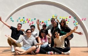 Members of Webflow’s design team pose together outdoors in front of a white wall decorated with colorful sticky notes.